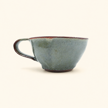 Blue ceramic cup with a handle on a white background