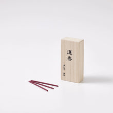 Wooden incense box with three red incense sticks on a white background