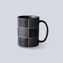 Black ceramic mug with grid pattern on a light gray background