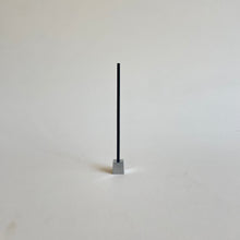 An Elemense Suou incense stick in a metal cube incense holder. 