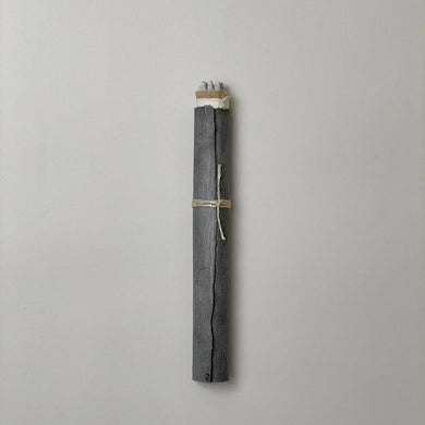 bundle of incense rolled in dark gray paper on a gray background