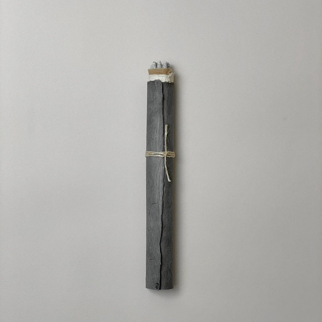 bundle of incense rolled in dark gray paper on a gray background
