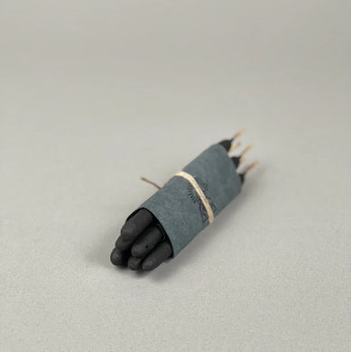 Black incense wrapped in gray paper on a light gray background