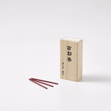 Wooden incense box with three red incense sticks on a white background