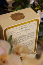 Decorative box with elegant design and text, surrounded by flowers.