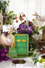 Green perfume bottle with decorative box on a table with flowers and candles
