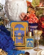 Luxurious perfume bottle with decorative packaging on a table with flowers and a vase.