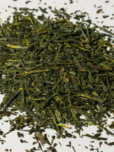 A close-up pile of loose-leaf green tea on a white background.