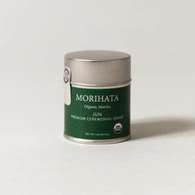 A silver metal tin of Morihata Organic Matricia Jun Premium Ceremonial Grade matcha green tea, set against a clean, light gray background.