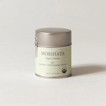 A small cylindrical metal tin of Morihata Organic Matcha Sei Classic Ceremonial Grade matcha tea, set against a clean, light gray background.