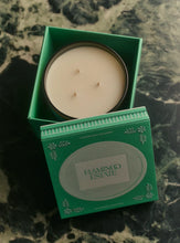 Candle in a green box with 'Flamingo Estate' branding on a textured surface