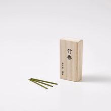 Wooden incense box with three green sticks on a white background