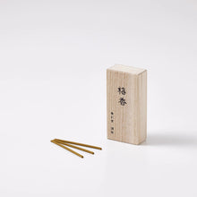 Wooden incense box with three incense sticks on a white background