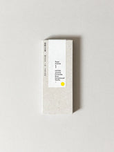 A tall, narrow rectangular box of paper incense Jasmine Coconut & Sandalwood Vanilla paper, shown on a neutral light gray background. The box is textured off-white with a central white label featuring black text and a small yellow dot.