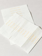 Four white textured paper incense with gold foil printed text, arranged diagonally on a light gray background.