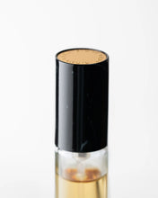 Small glass bottle with a black cap on a white background