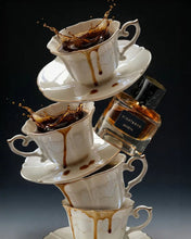Stack of white teacups with coffee splashes and a bottle of Eight & Bob on a dark background