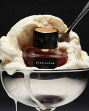Perfume bottle labeled 'Eight & Bob' on a scoop of ice cream with a spoon.