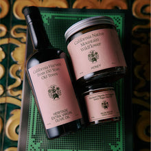 Bottle of California Harvest Extra Virgin Olive Oil and jars of California Native Mountain Flower Honey, and Salsa Macha on a decorative surface.