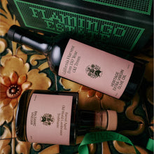 Two bottles of olive oil and balsamic vinegar with pink labels on a decorative surface.