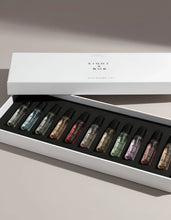 Set of small bottles with colorful perfumes in a 'EIGHT by Bob' box on a light background