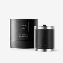 Two black scented candles with silver accents on a white background