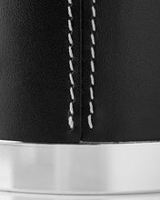 Close-up of a black candle holder with white stitching and silver base.
