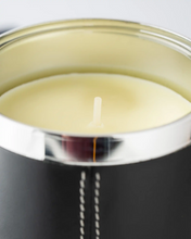 Close-up of a candle in a black container with a silver lid.