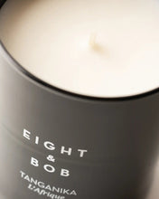 Close-up of a candle in a black container with 'Eight & Bob' branding.
