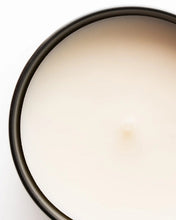 Close-up of candle with a white shade and black vessel on a white background