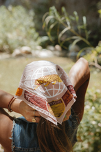 A person wearing Bandit Bandana - "Venture with Curiosity" (Beige) - Airstream X Bandits as a hear scarf