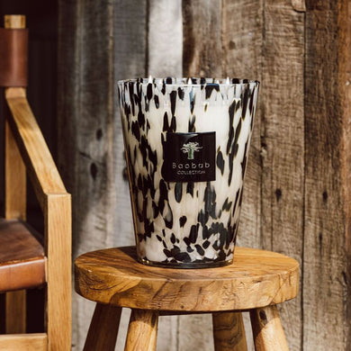 Decorative candle vessel with a leopard print pattern on a wooden stool against a rustic wooden wall.