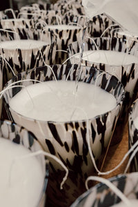 Hand poured candle with black and white patterned rims on a wooden surface