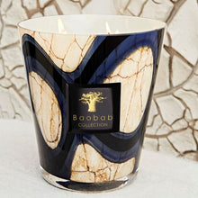 Decorative candle with Baobab Collection logo against a textured wall.