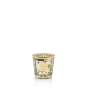 Decorative candle in a glass holder with intricate design on a white background