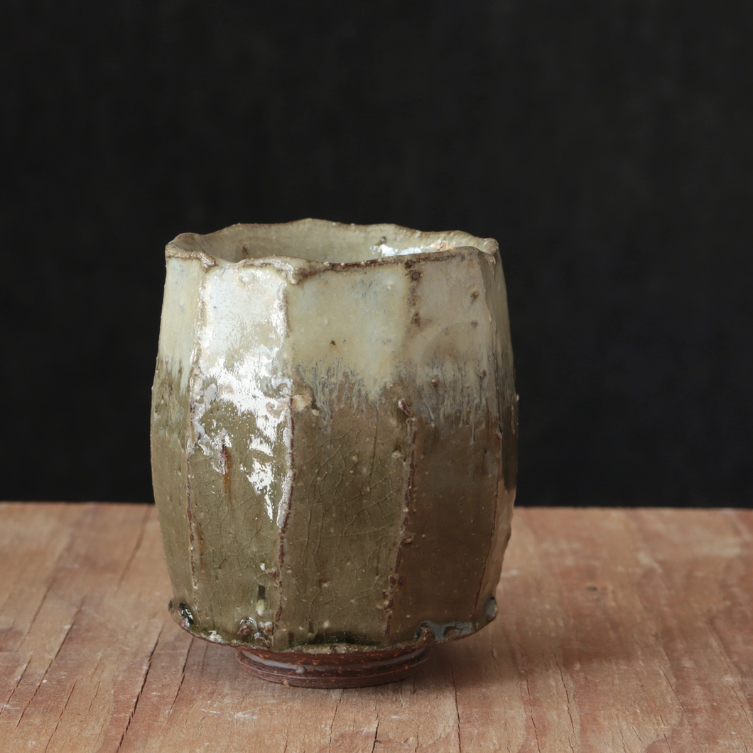 Green and white glaze tea cup on rustic wood table