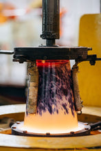 Close-up of a ceramic or glass product being shaped by a machine with a blurred background