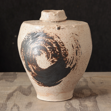 Ceramic jar with black abstract design on a textured surface