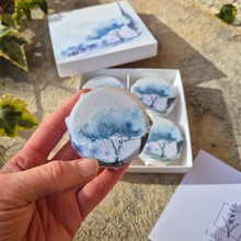 Hand holding a blue and white soap with packaging in the background.