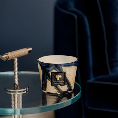 Candle on a glass table with a dark blue armchair in the background