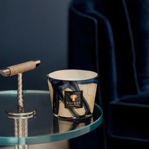 Candle on a glass table with a dark blue armchair in the background