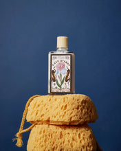 Bottle of Lait d'Iris milk on a yellow sponge against a blue background