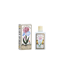 A bottle of Lait D'Iris Elixir de Parfum next to its illustrated packaging box, featuring vintage-style drawings of irises on a white background.