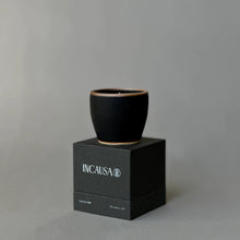 Black ceramic cup on a black box with 'INCAUSA' branding against a gray background
