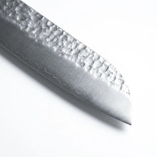 Close-up of a knife blade with textured surface on a white background