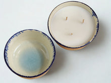 Two ceramic bowls with a blue and beige glaze, one showing a light blue gradient interior and the other showing a white wax surface with three wicks, photographed on a plain white background.