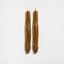 Two brown twisted candles on a white background