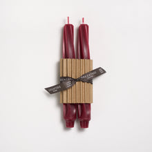 Two red candles tied with a brown ribbon on a white background