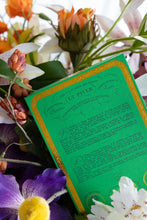 Green box with gold surrounded by colorful flowers