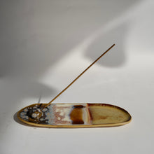An incense stick in a large elongated oval ceramic Incense Dish. 